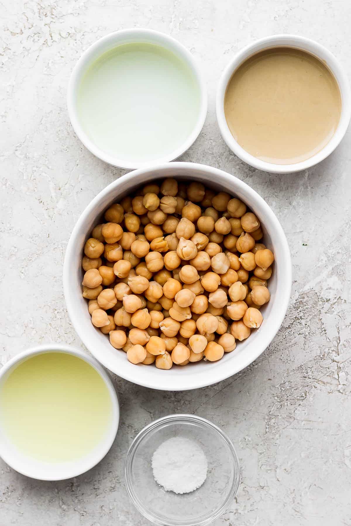 The ingredients for roasted garlic hummus in separate bowls.