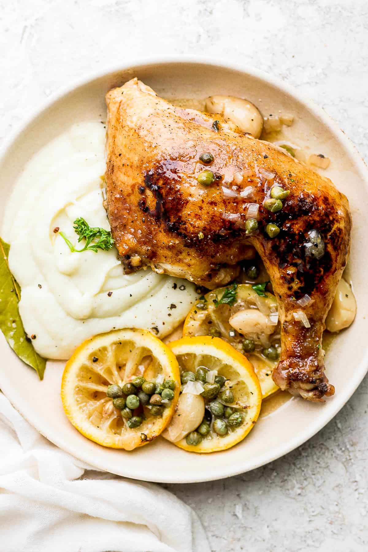 Cauliflower mash on a plate with braised lemon garlic chicken.