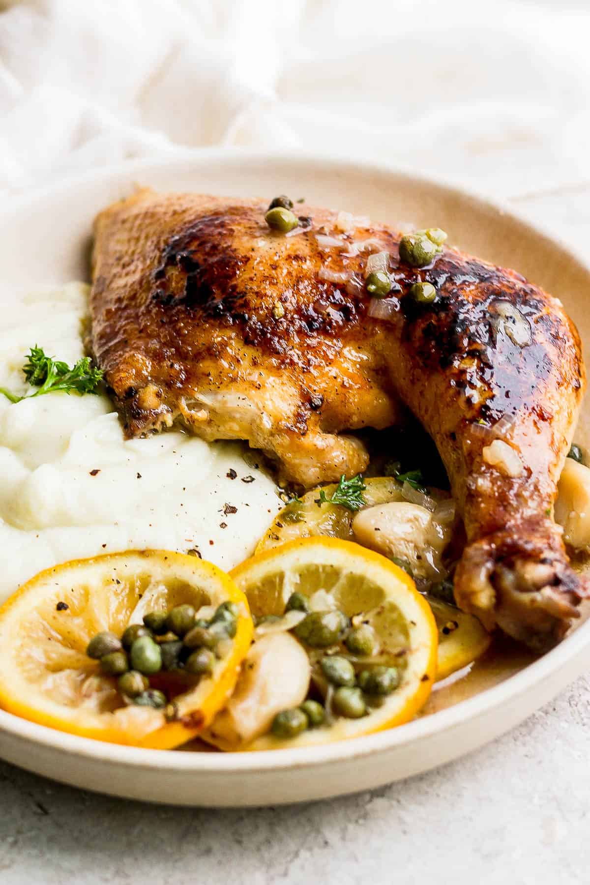 Another image of a serving of lemon garlic chicken with mashed cauliflower on a plate.