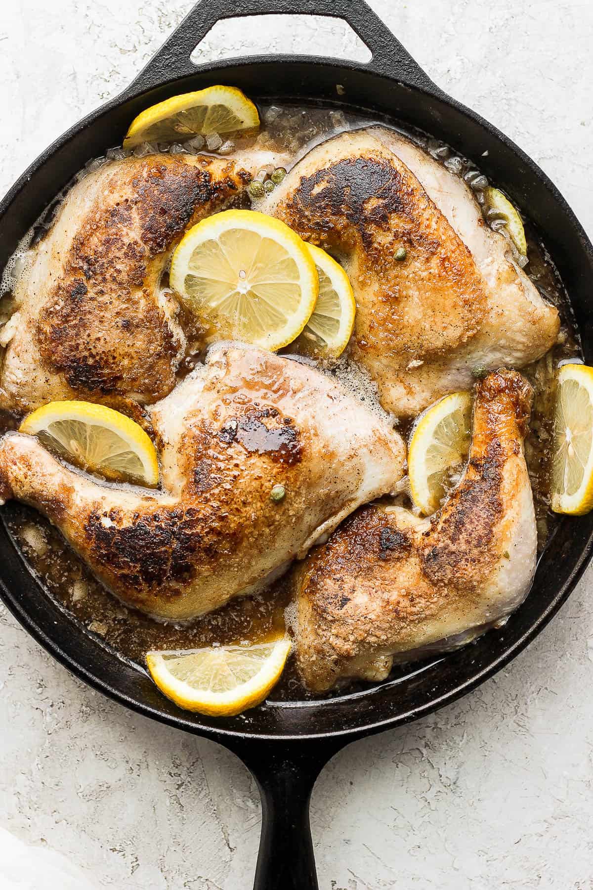 Capers, lemon slices, and garlic added to the skillet and the chicken nestled on top.