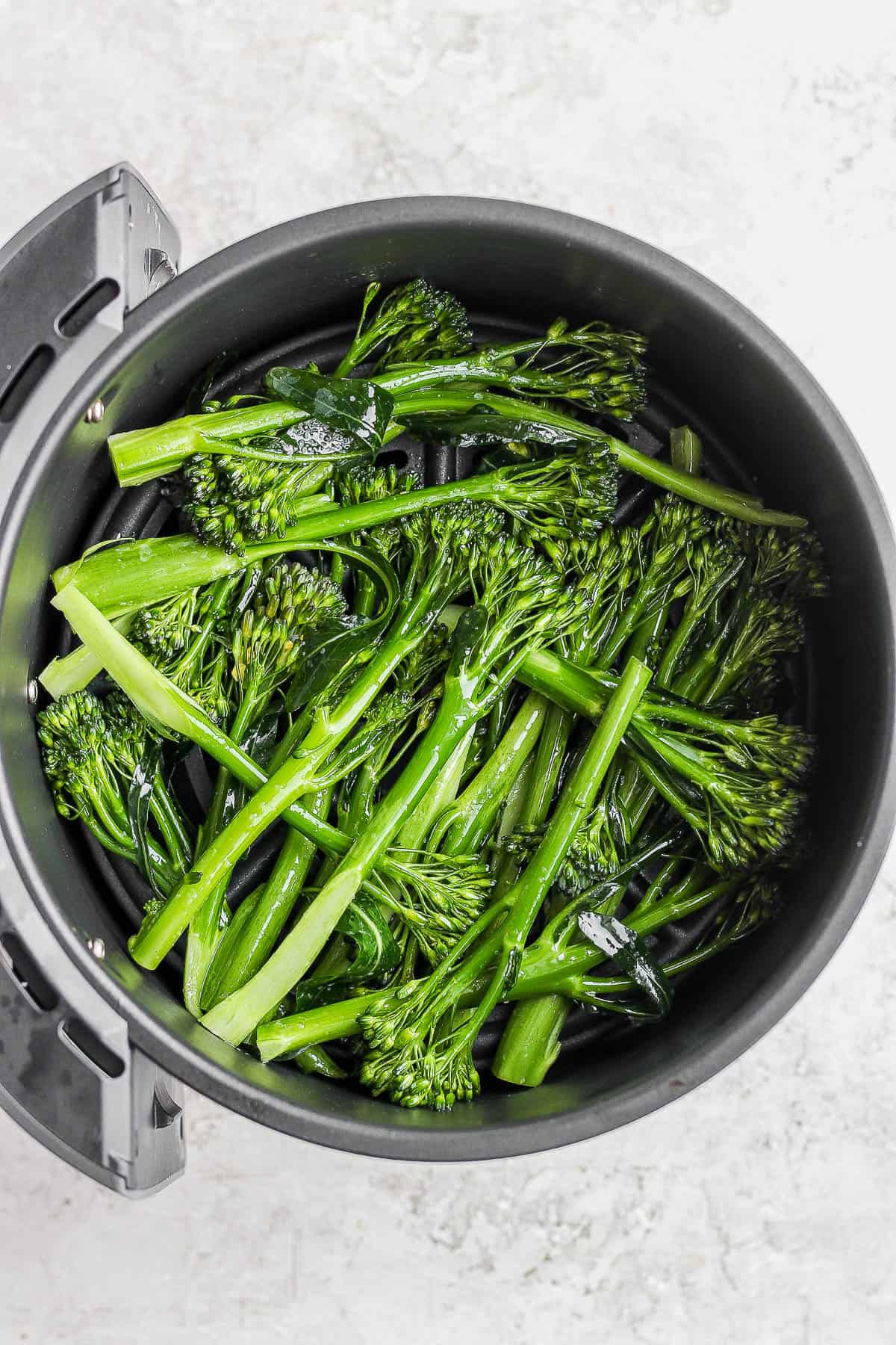 Prepared broccolini in the air fryer basket.