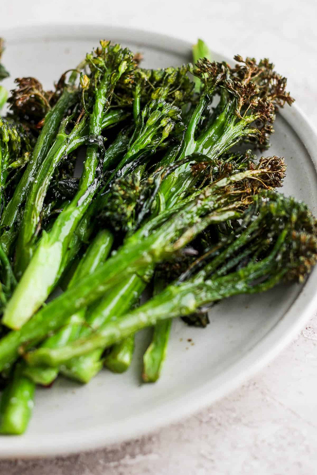 Air fried broccolini on a white plate.