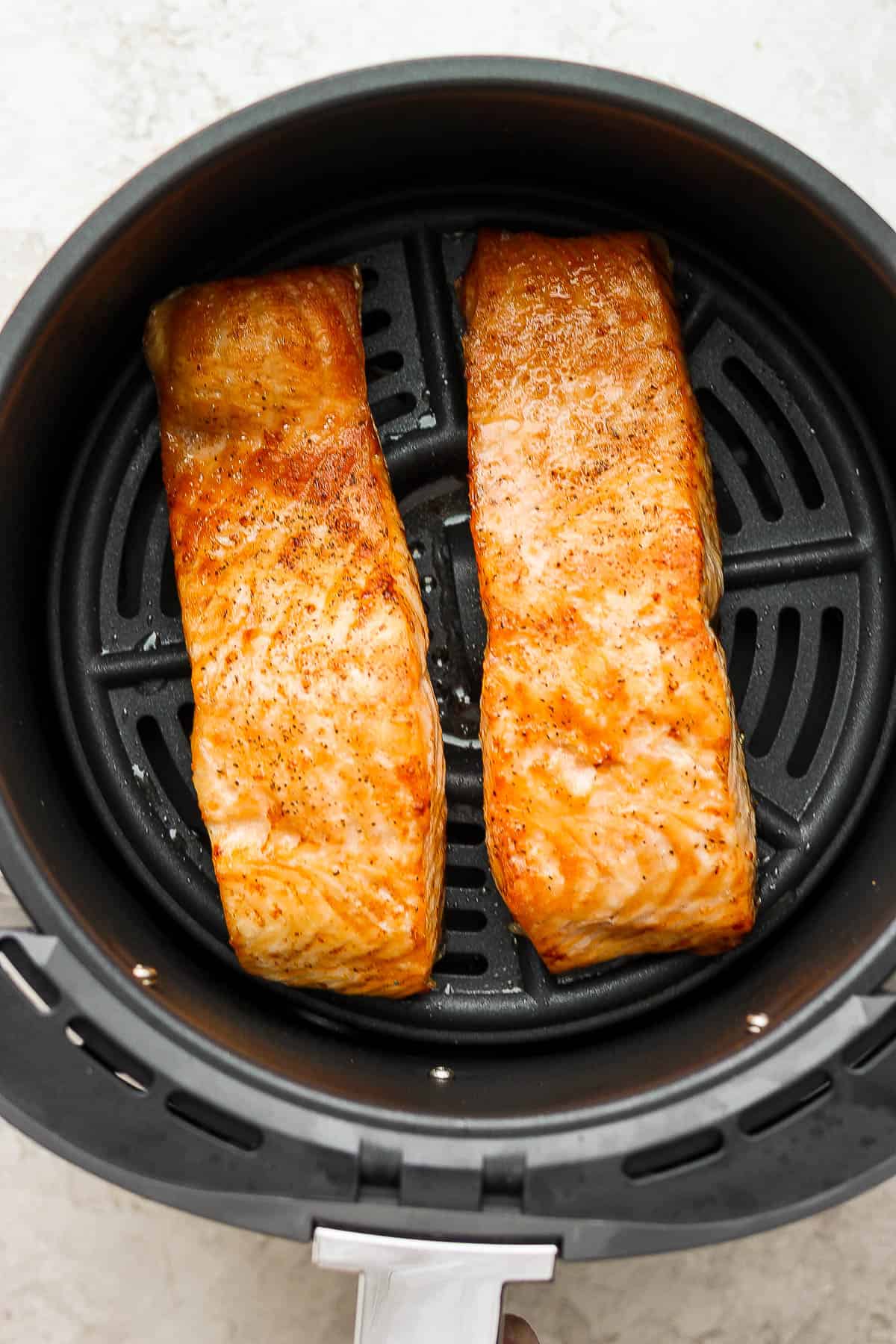 Air fried salmon fillets in the basket after being cooked.