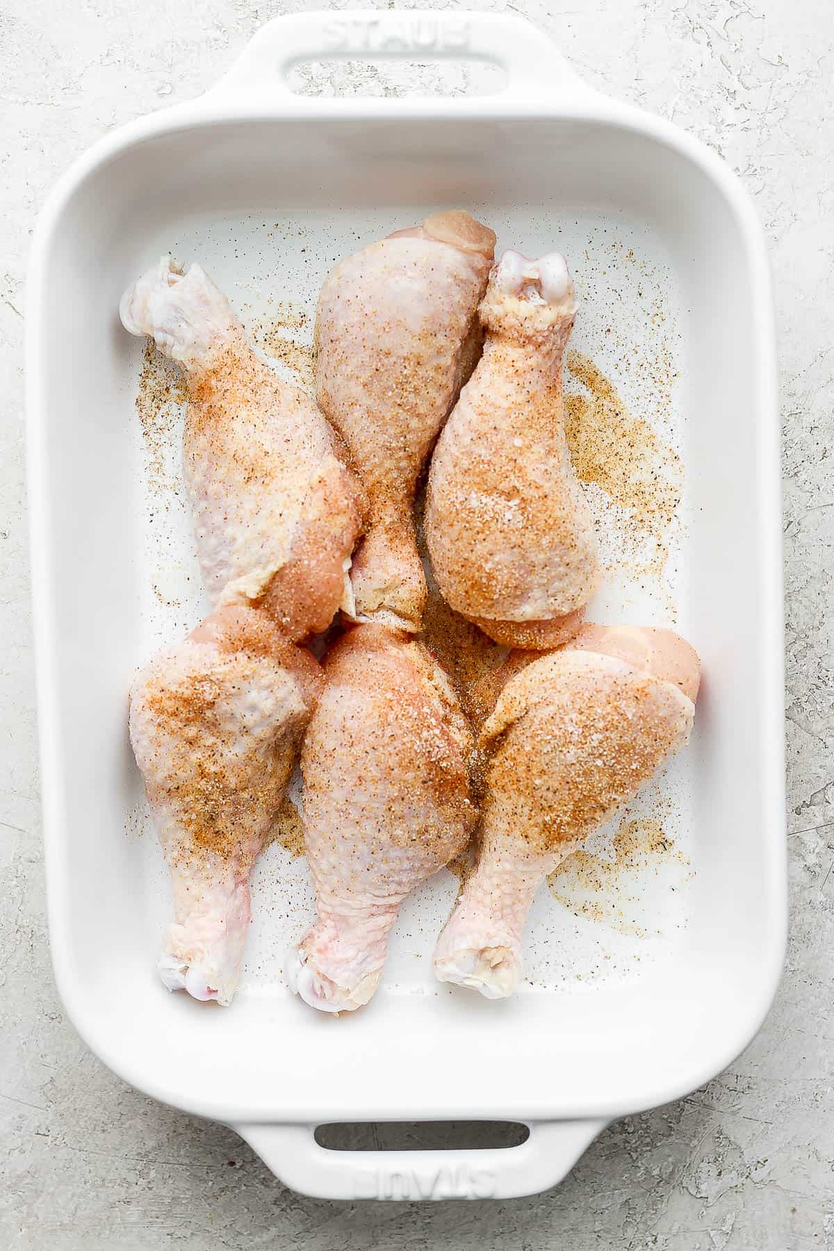 Raw chicken legs rubbed down in olive oil and then sprinkled with the seasoning mixture.