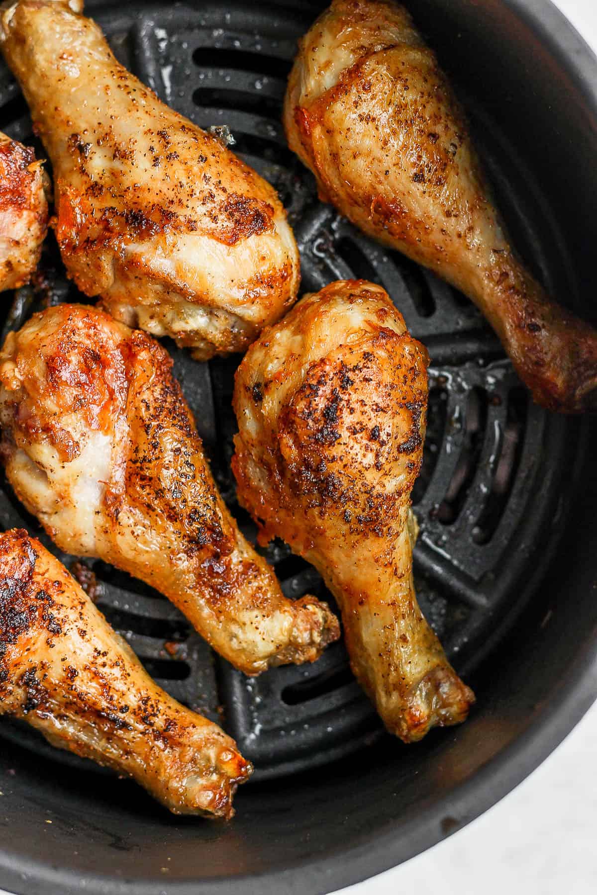 Air fried chicken legs in the air fryer basket.