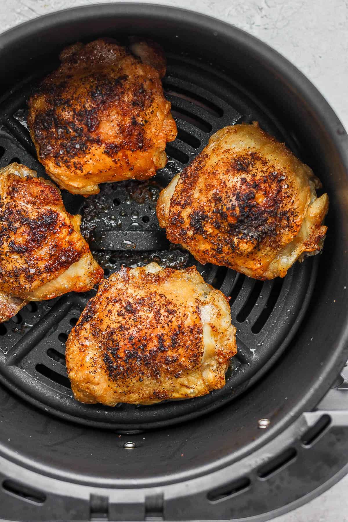 Air fried chicken thighs in the air fryer basket.