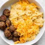 Bowl of cheesy orzo with beef meatballs.