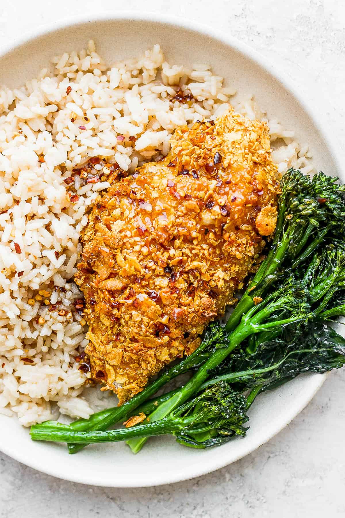Hot honey chicken on a plate with rice and broccolini.