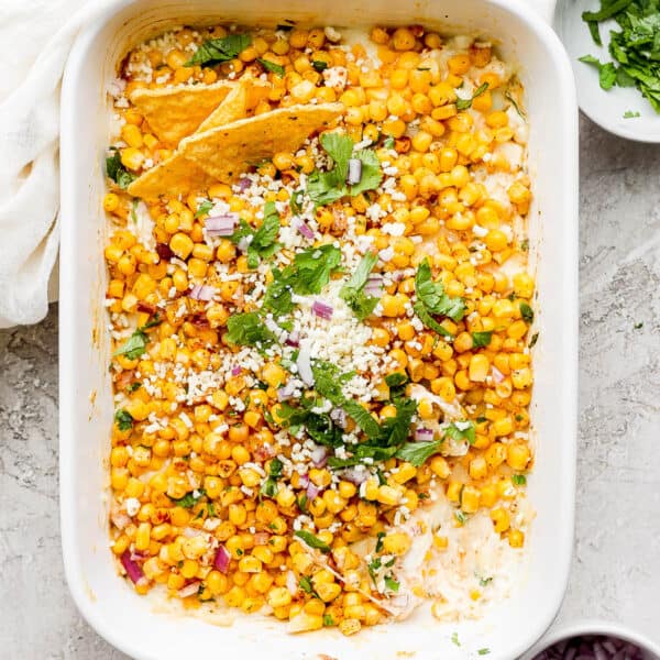 Pan of Mexican Street Corn Dip with a few chips sticking out and garnished with fresh cilantro and chopped cilantro.