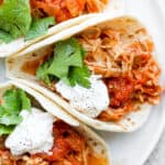 A plate of salsa chicken tacos with sour cream and fresh cilantro.