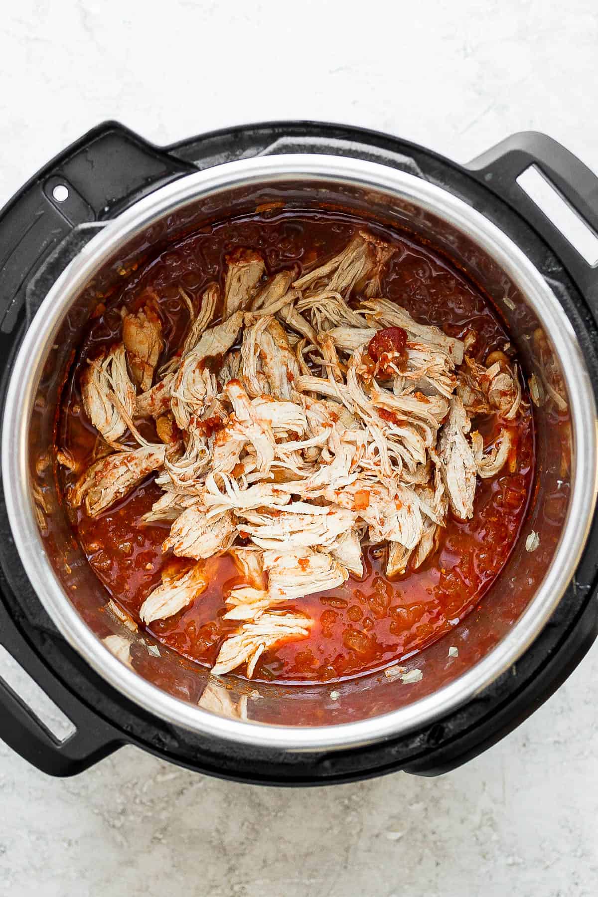 Shredded chicken placed back into the instant pot with the salsa mixture.
