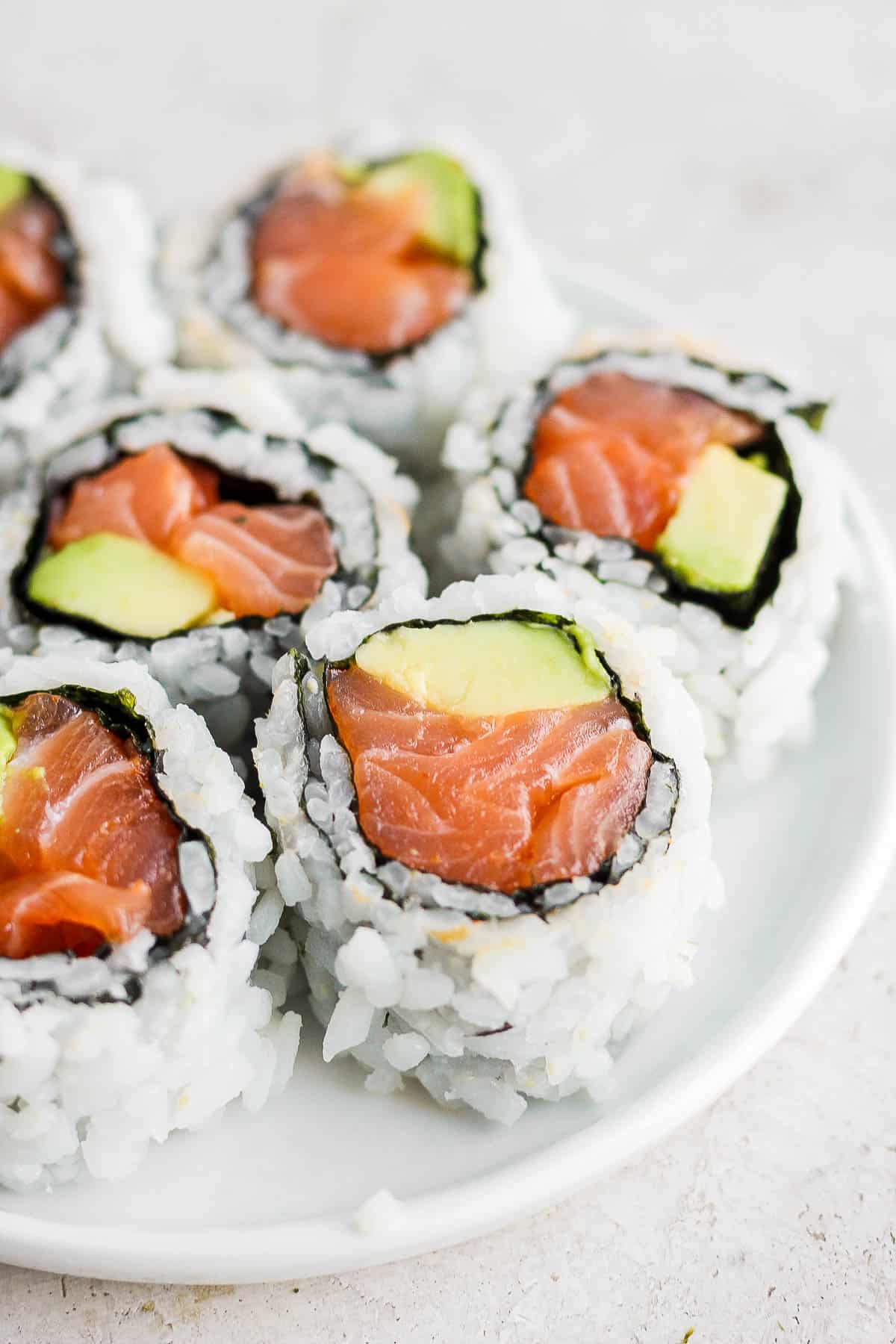 Pieces of a spicy salmon roll on a white plate.