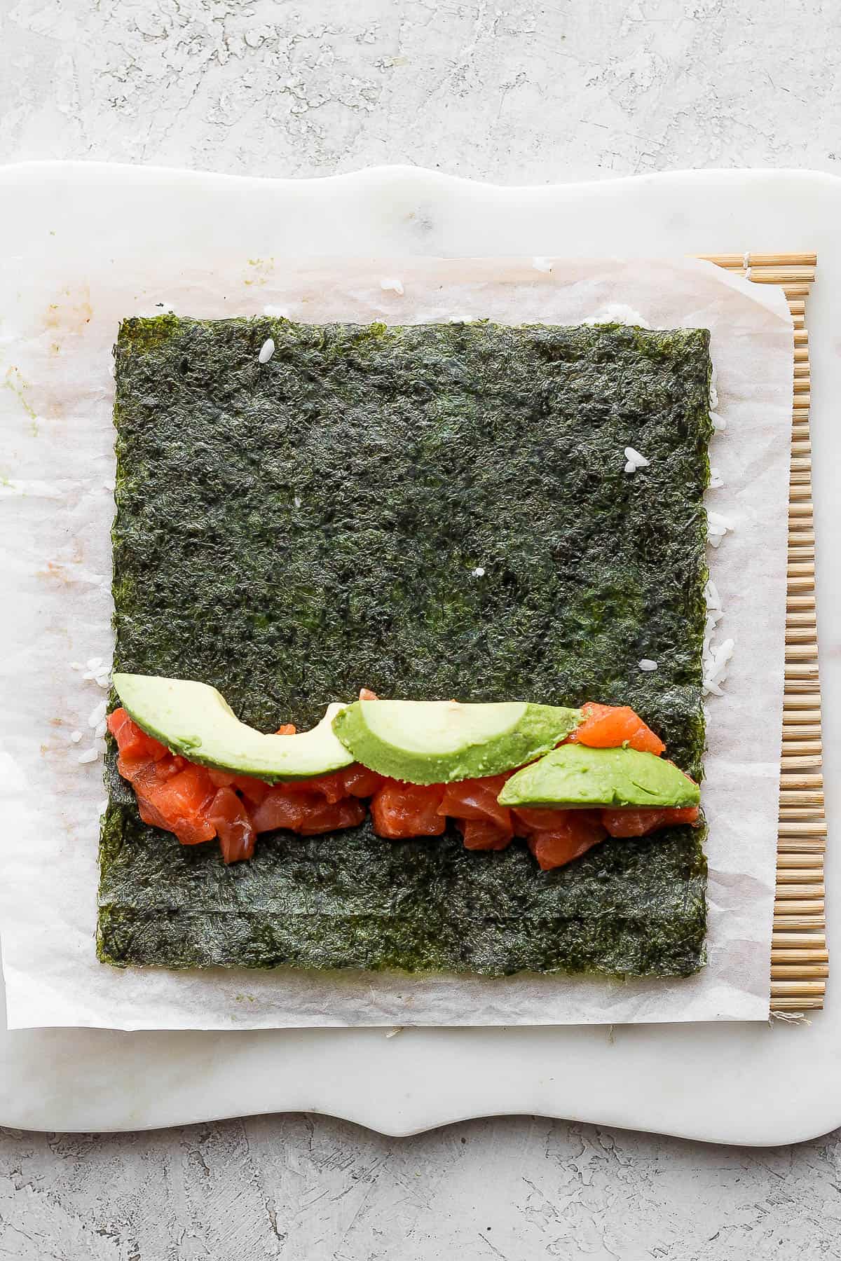 The filling ingredients added towards the bottom of the nori sheet.