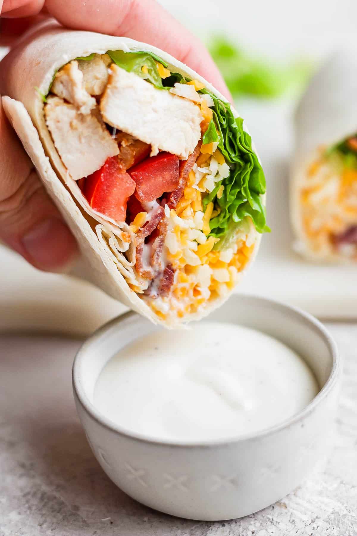 Half of a wrap being dipped in ranch.