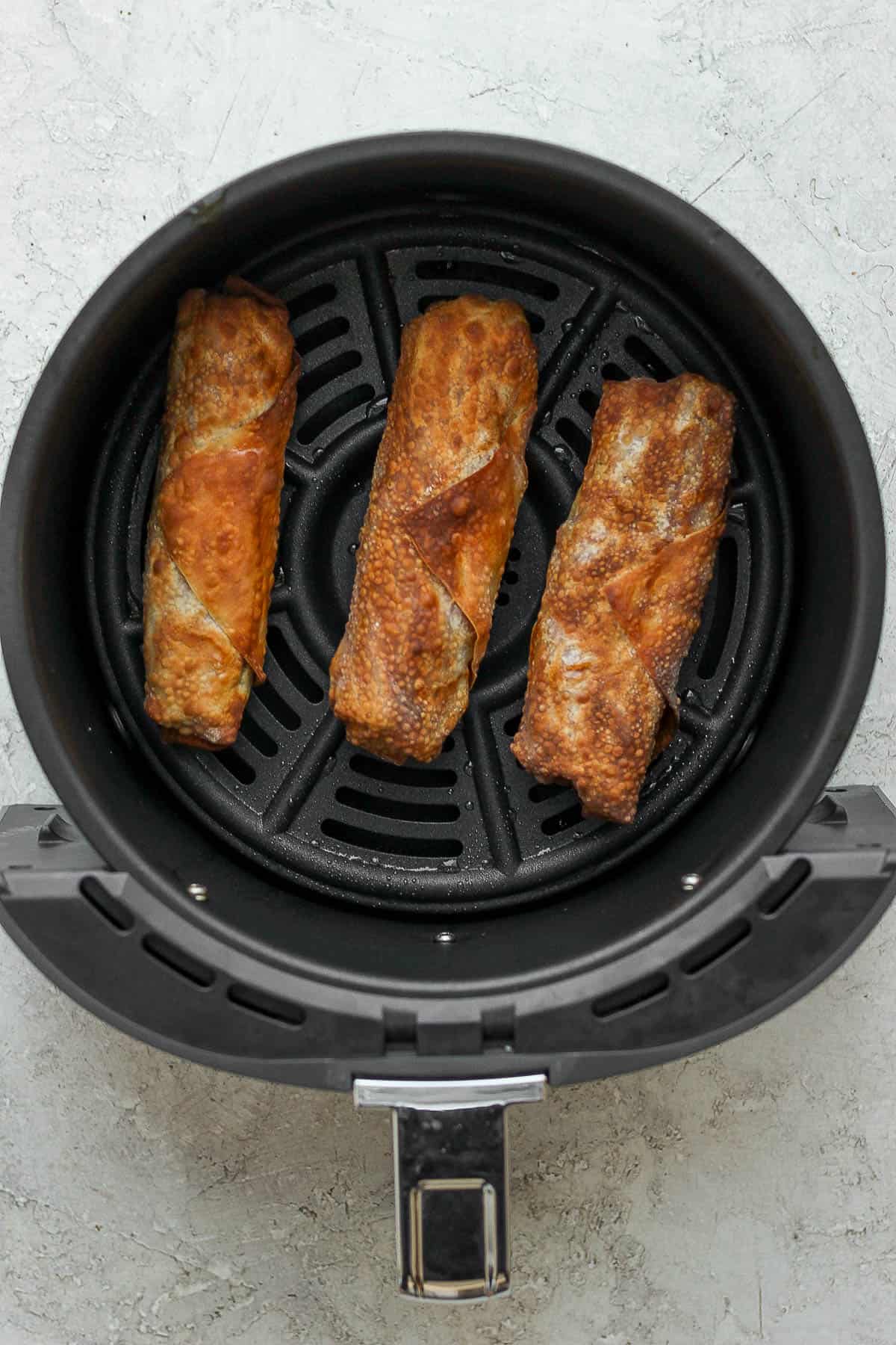 Air fried corned beef and cabbage egg rolls in an air fryer basket.
