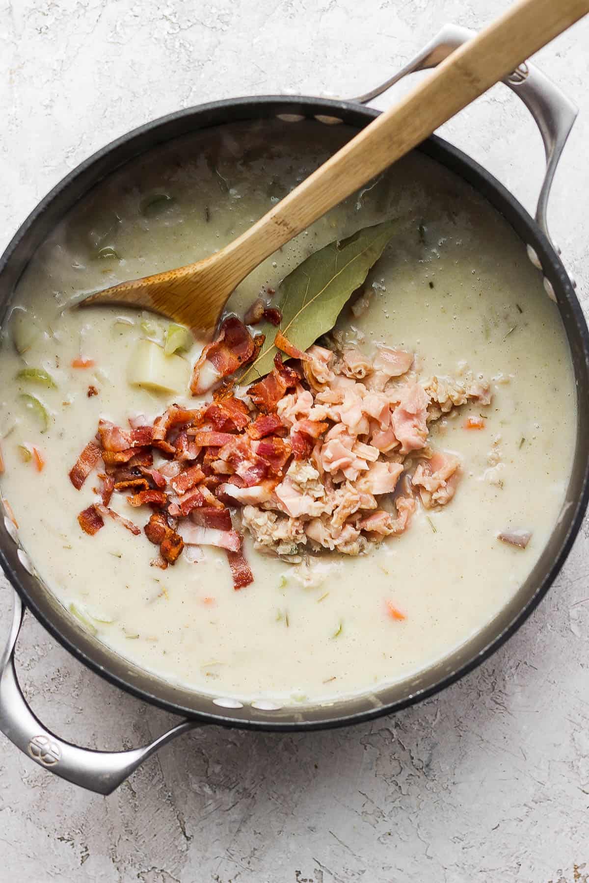 Canned clams with juice, bacon bits, and bay leaf added into the pot.