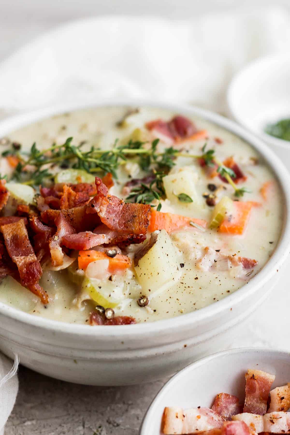Another few of dairy free clam chowder in a bowl with bacon and herbs on top.