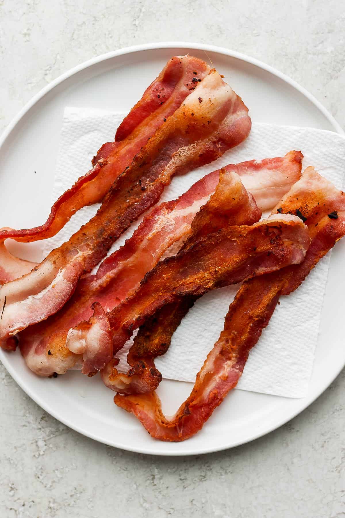 Cooked bacon strips on a paper towel-lined plate.