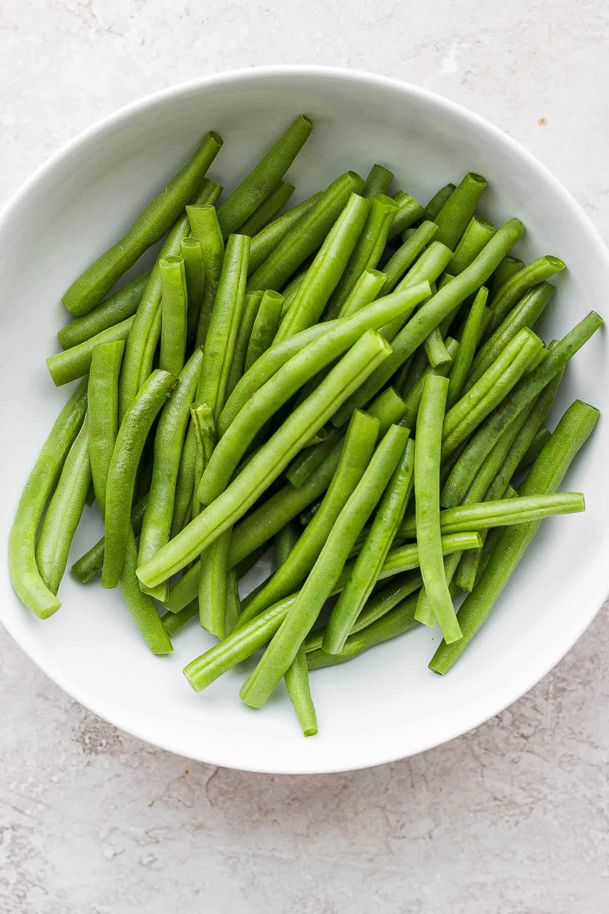Clean and trimmed green beans on a plate.