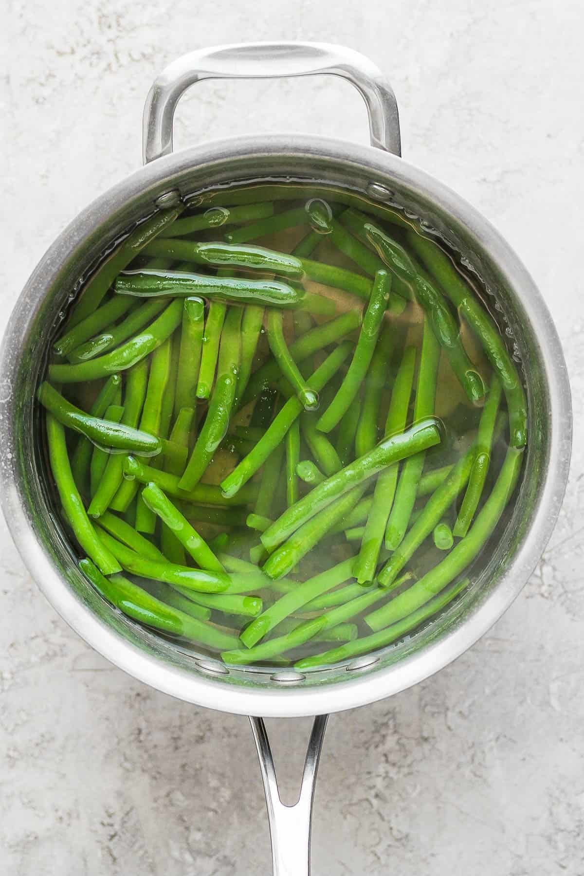Green beans submerged in boiling water in a sauce pan.