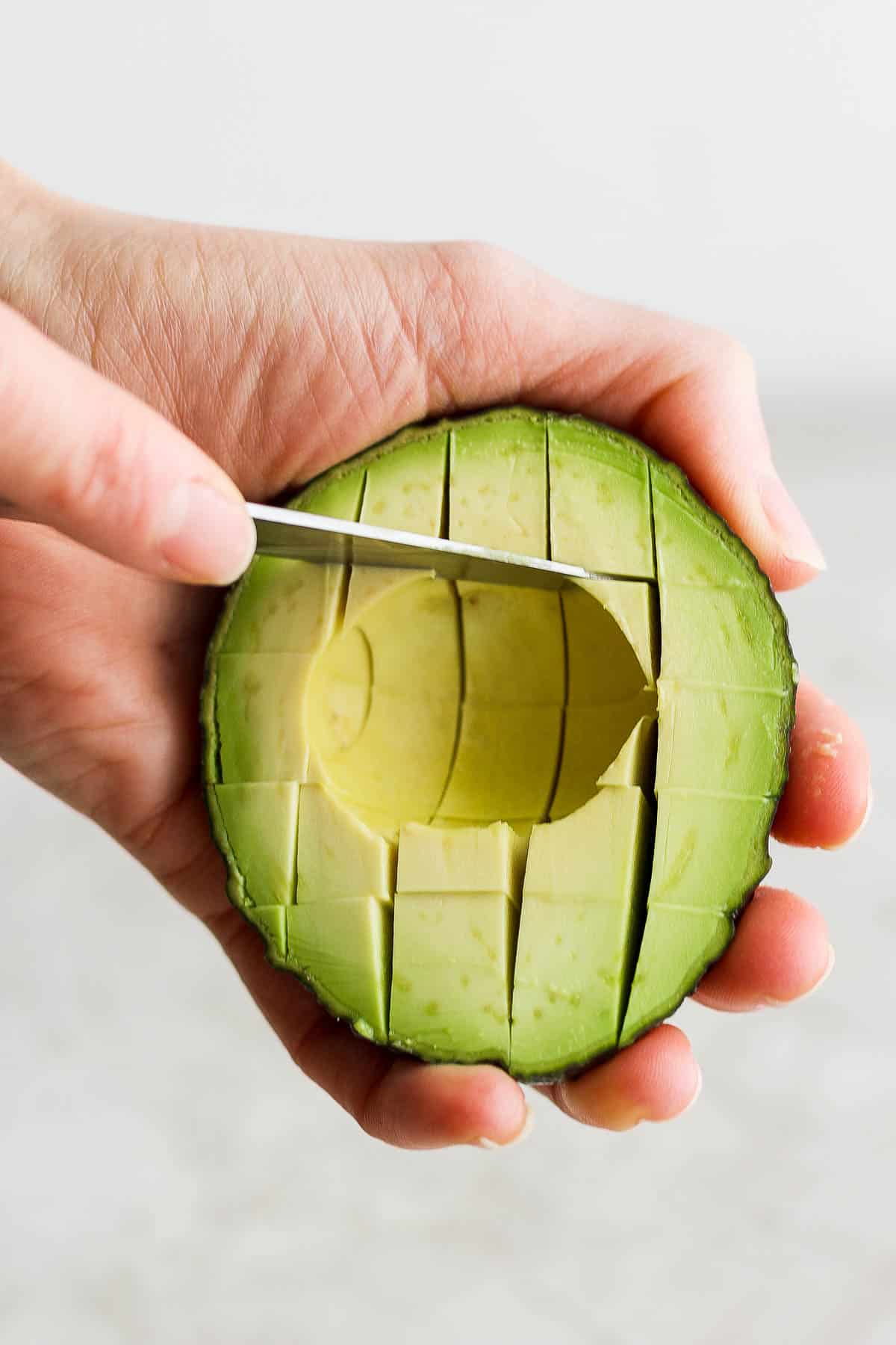 An avocado half that has also been sliced horizontally in order to dice it into pieces.