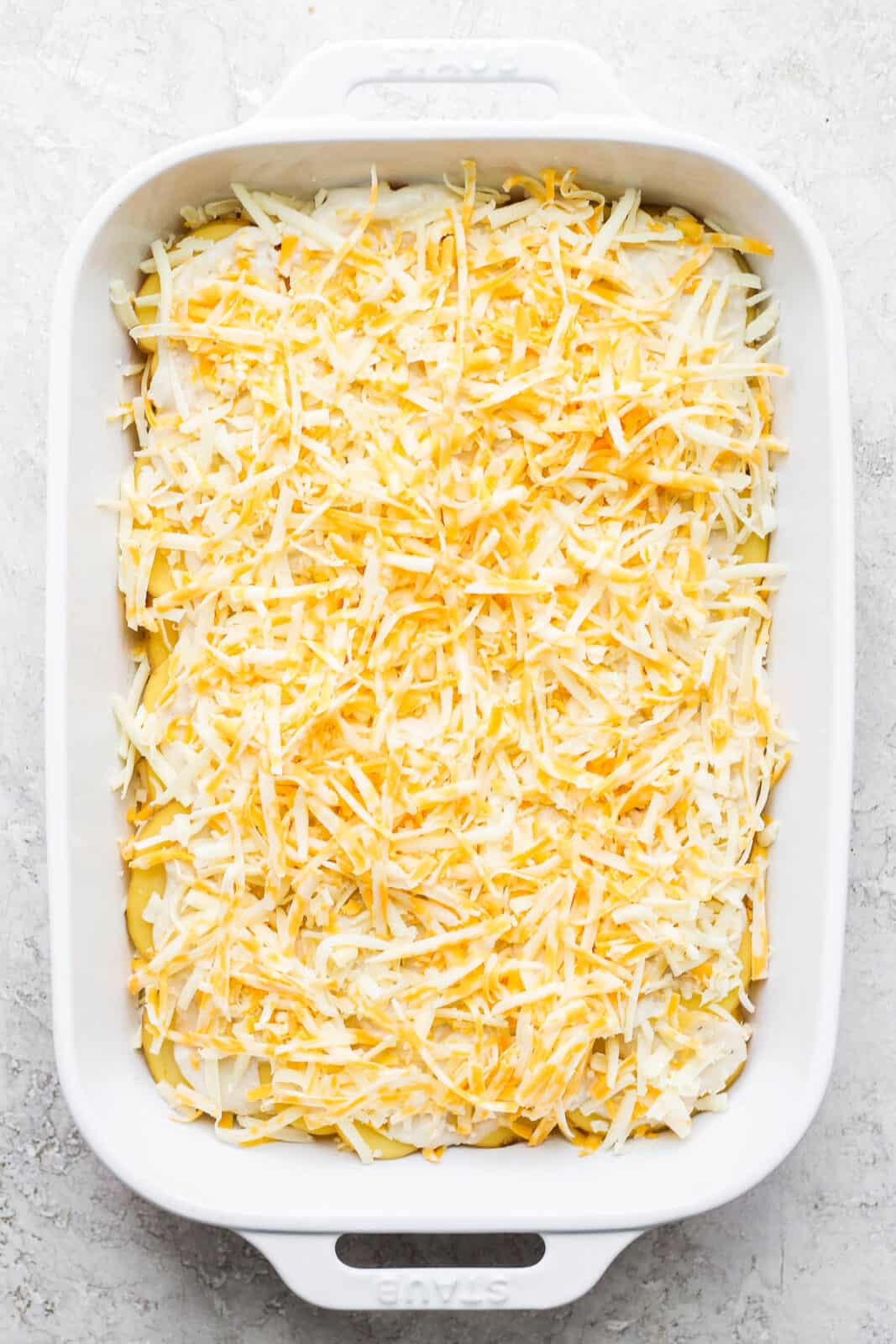 Another layer of cream sauce and shredded cheese added on top of the second layer of sliced potatoes.