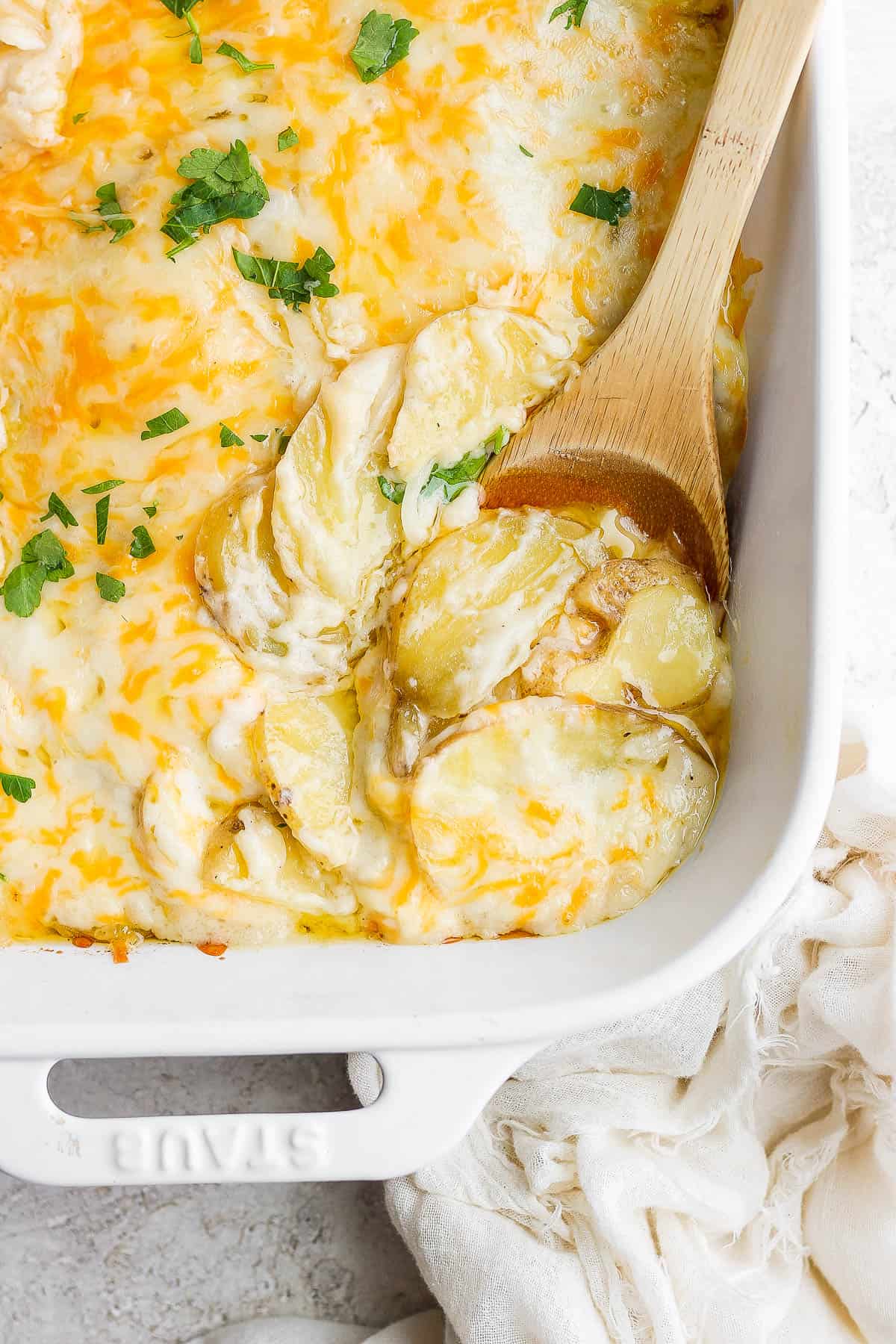 A wooden spoon in the scalloped potatoes.