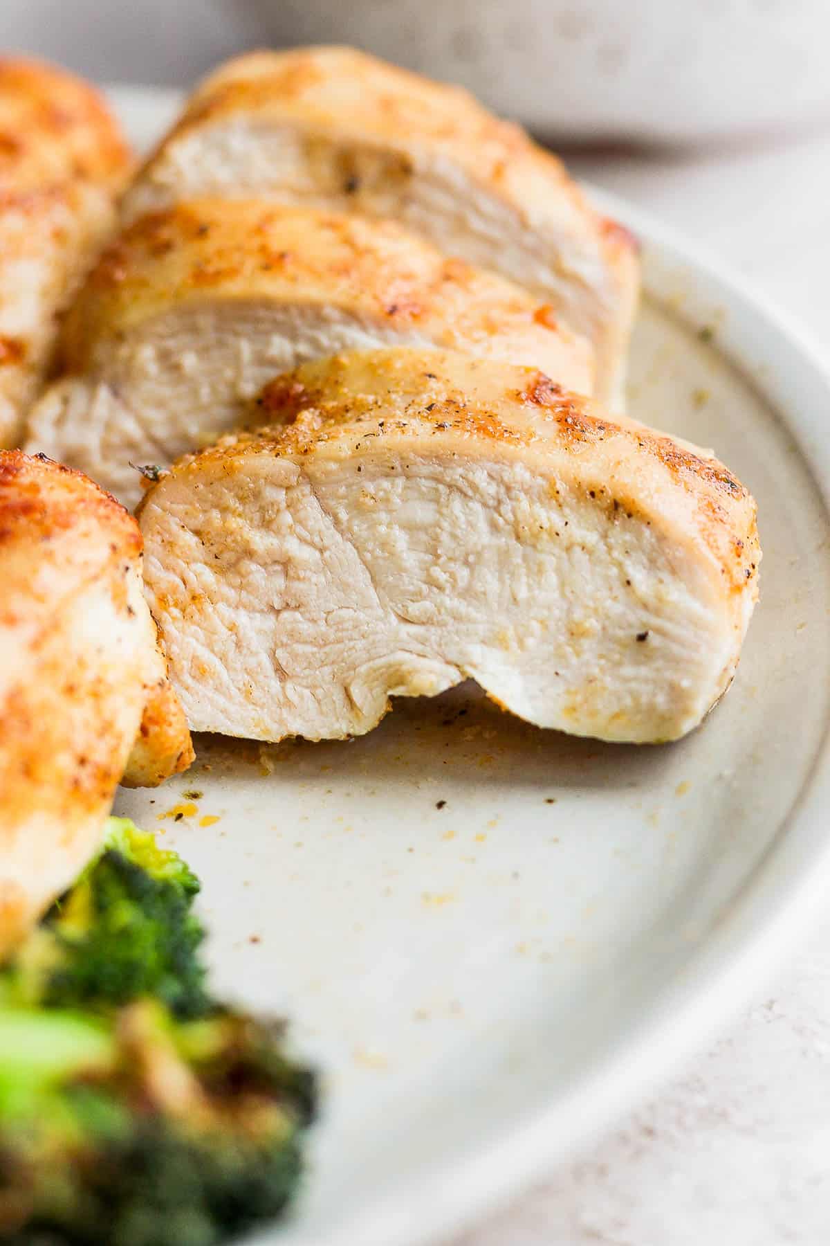 An air fryer chicken breast cut into strips on a plate.