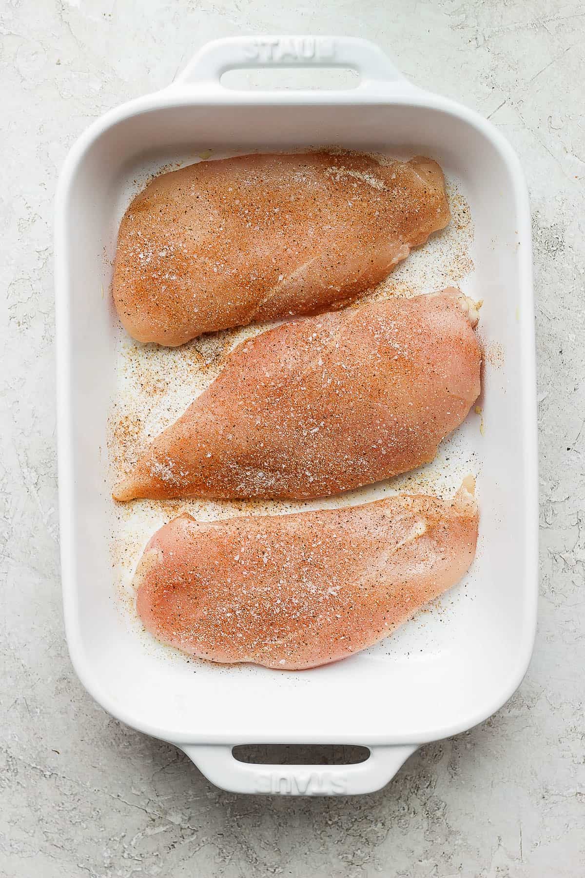Chicken breasts covered in olive oil and seasoned with the seasoning mixture.