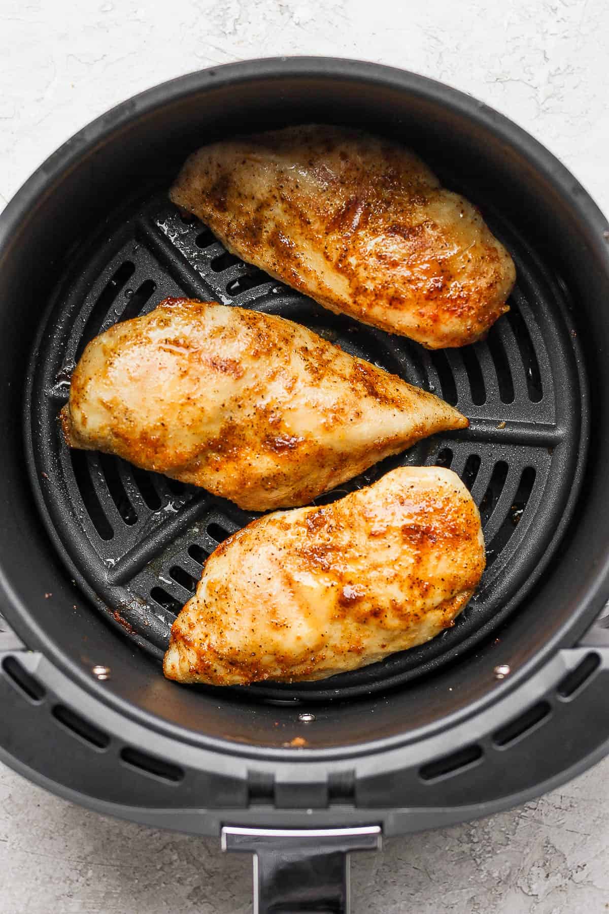 Perfectly air fried chicken breasts in the air fryer basket.