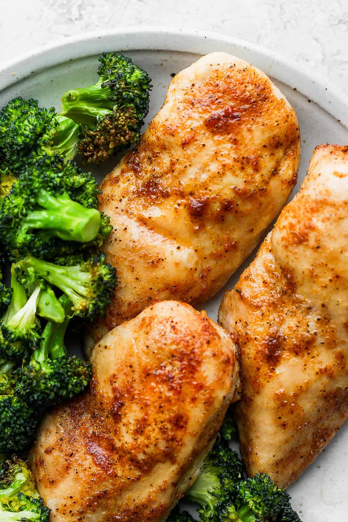 Air fried chicken breasts on a plate with air fried broccoli.