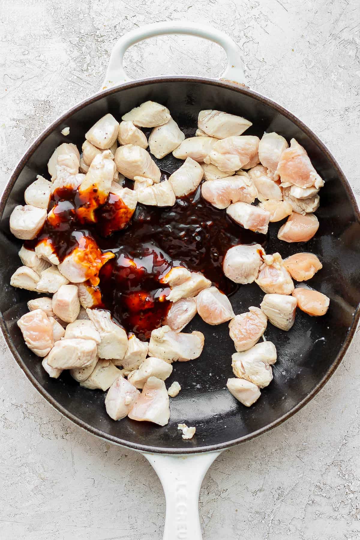 Teriyaki sauce added to the skillet with the chicken.