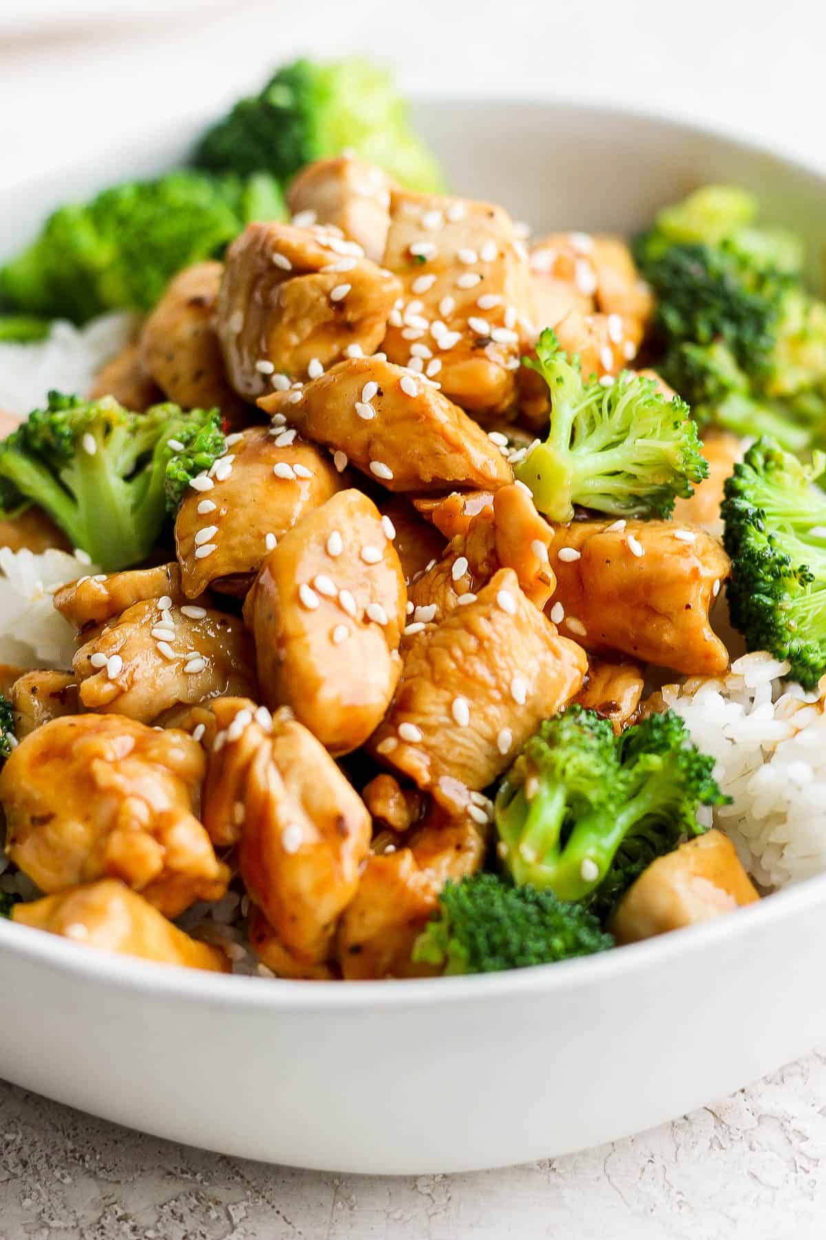 A white bowl with chicken teriyaki, broccoli, and white rice.