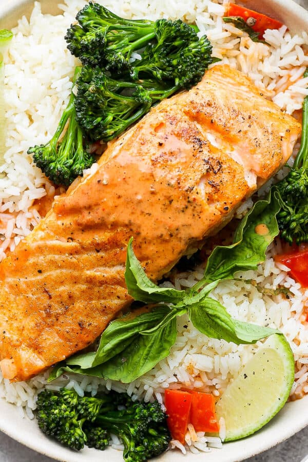 A bowl of rice with broccoli and a piece of coconut curry salmon.