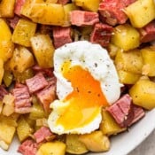 An up close shot of a bowl of corned beef hash with a poached egg on top.