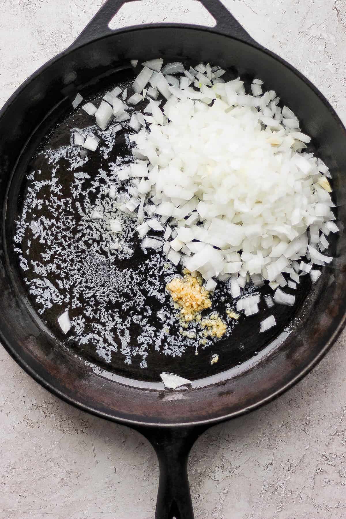 Melted butter, minced garlic, and diced onion in a cast iron skillet.