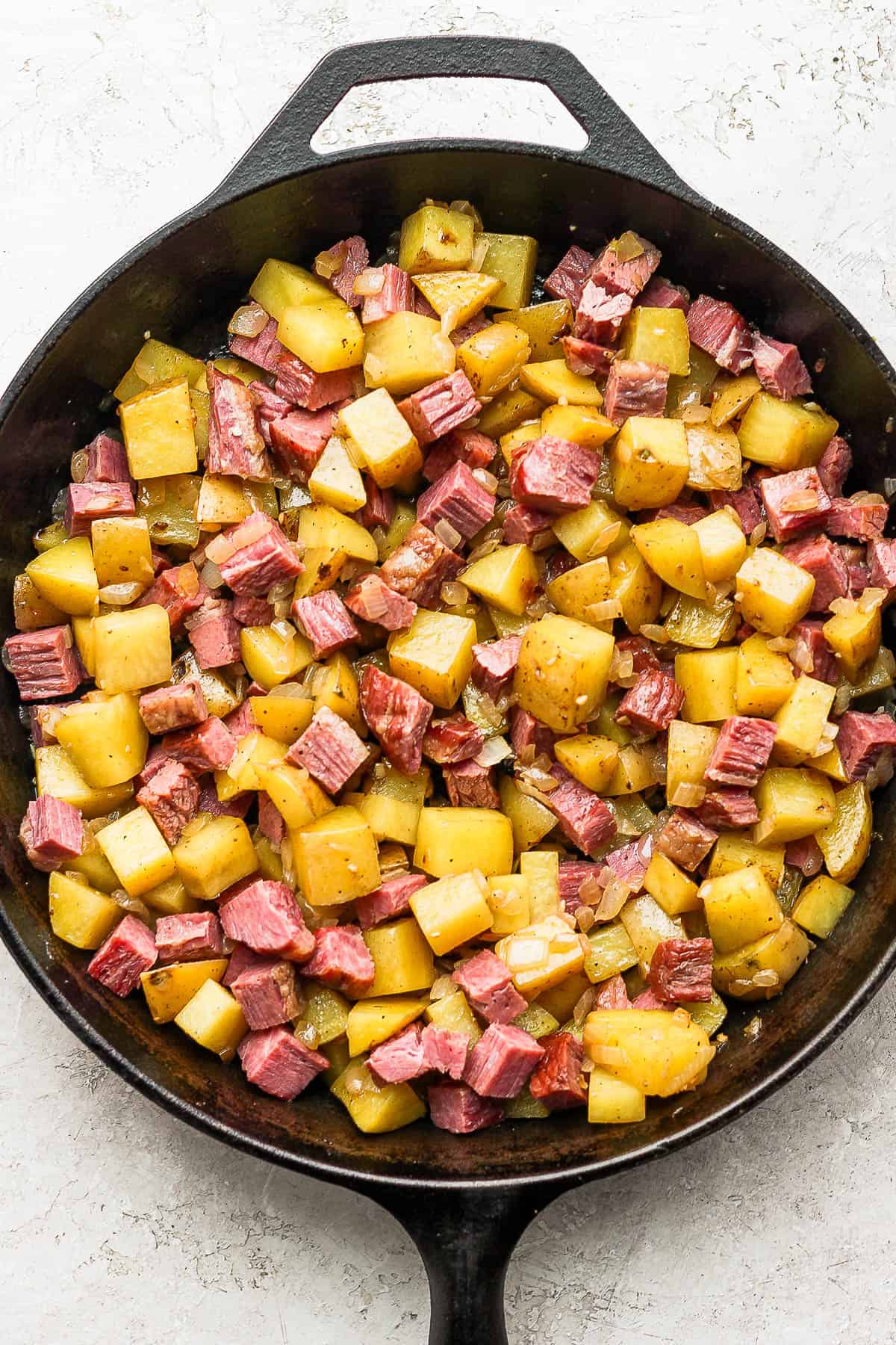 The corned beef, cubed potatoes, onions, garlic and butter mixed together in the skillet. 
