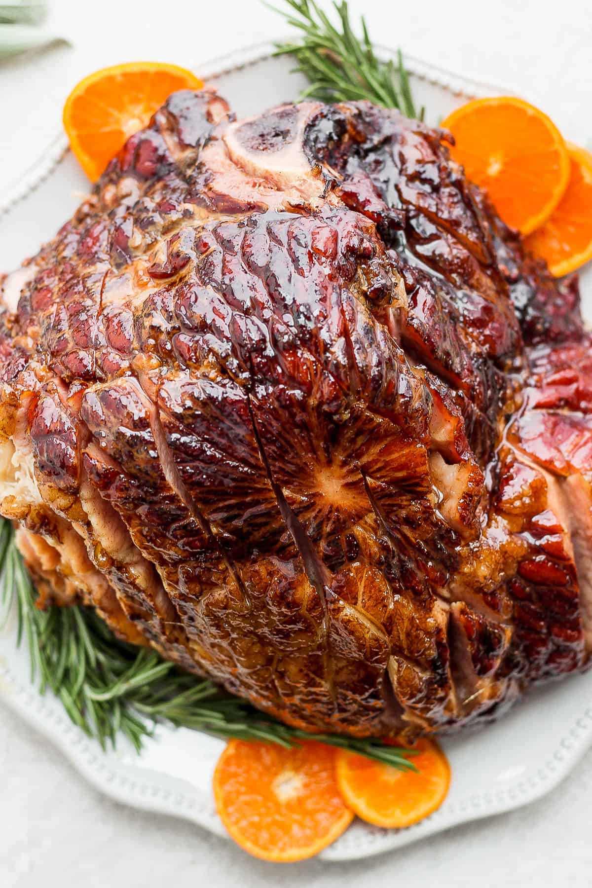 Crockpot ham resting on a large white platter.