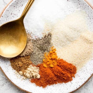 Dry rub for ribs spices on a plate with a gold spoon.