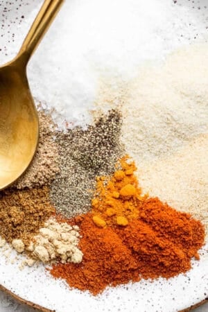 Dry rub for ribs spices on a plate with a gold spoon.