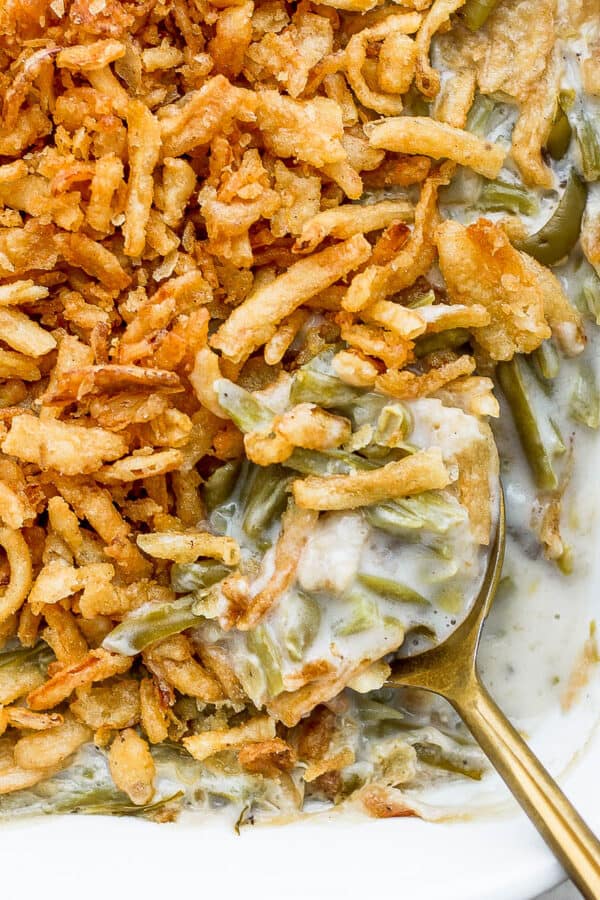 The corner of a casserole dish filled with easy green bean casserole and topped with french fried onions.