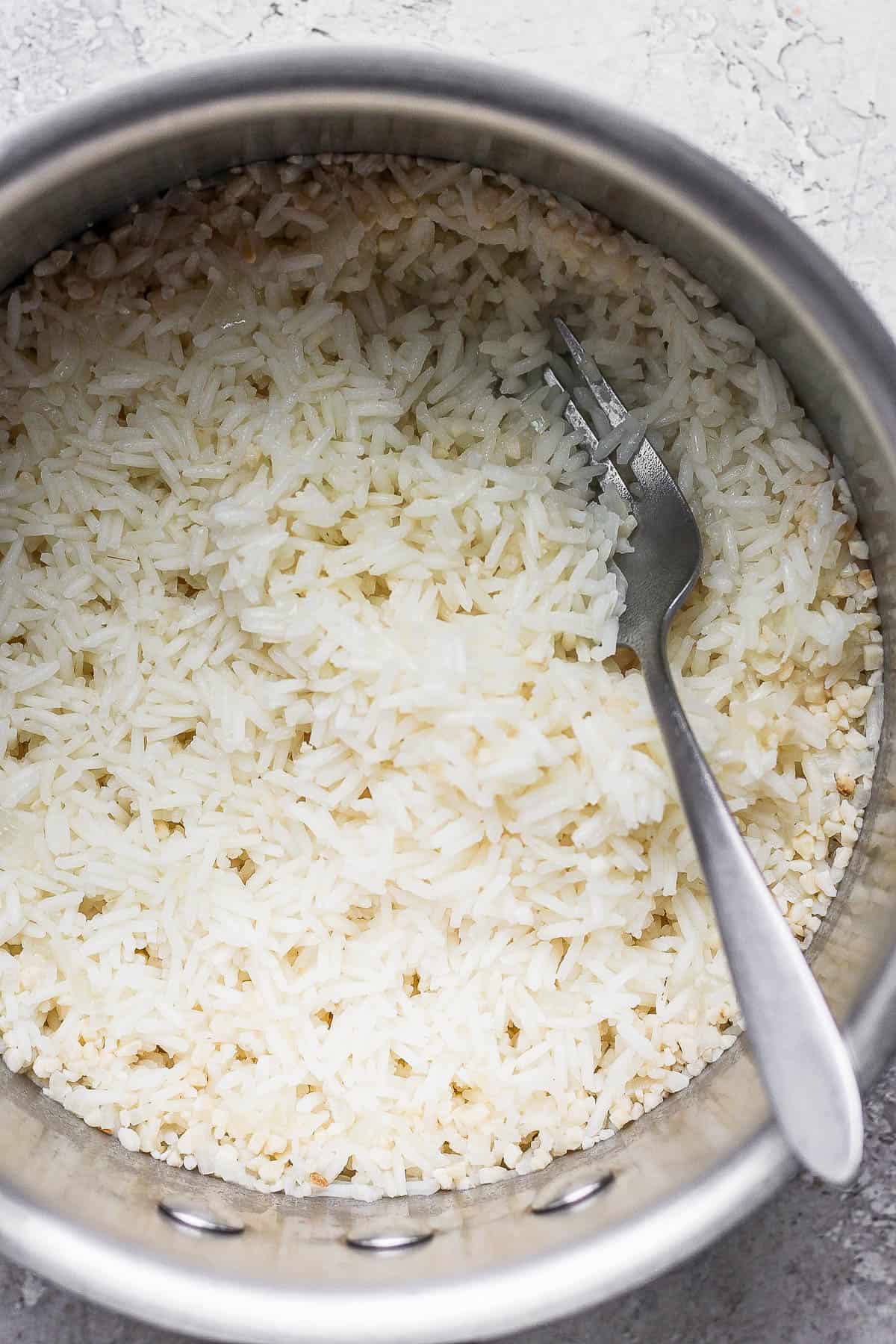 A fork fluffing the rice in the pot.