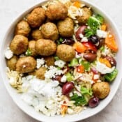 A bowl of greek orzo with greek turkey meatballs and some tzatziki sauce.
