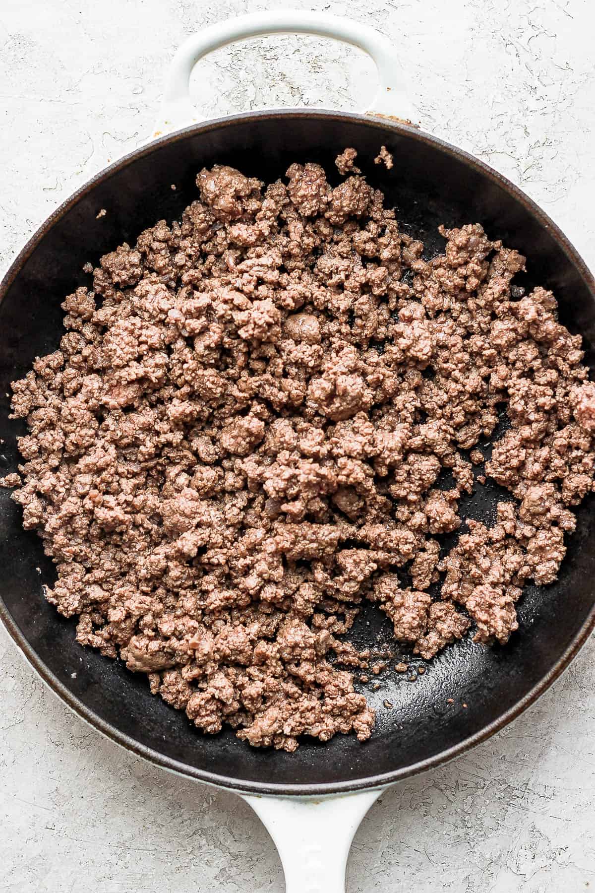 Crumbled and cooked ground beef in a cast iron skillet.