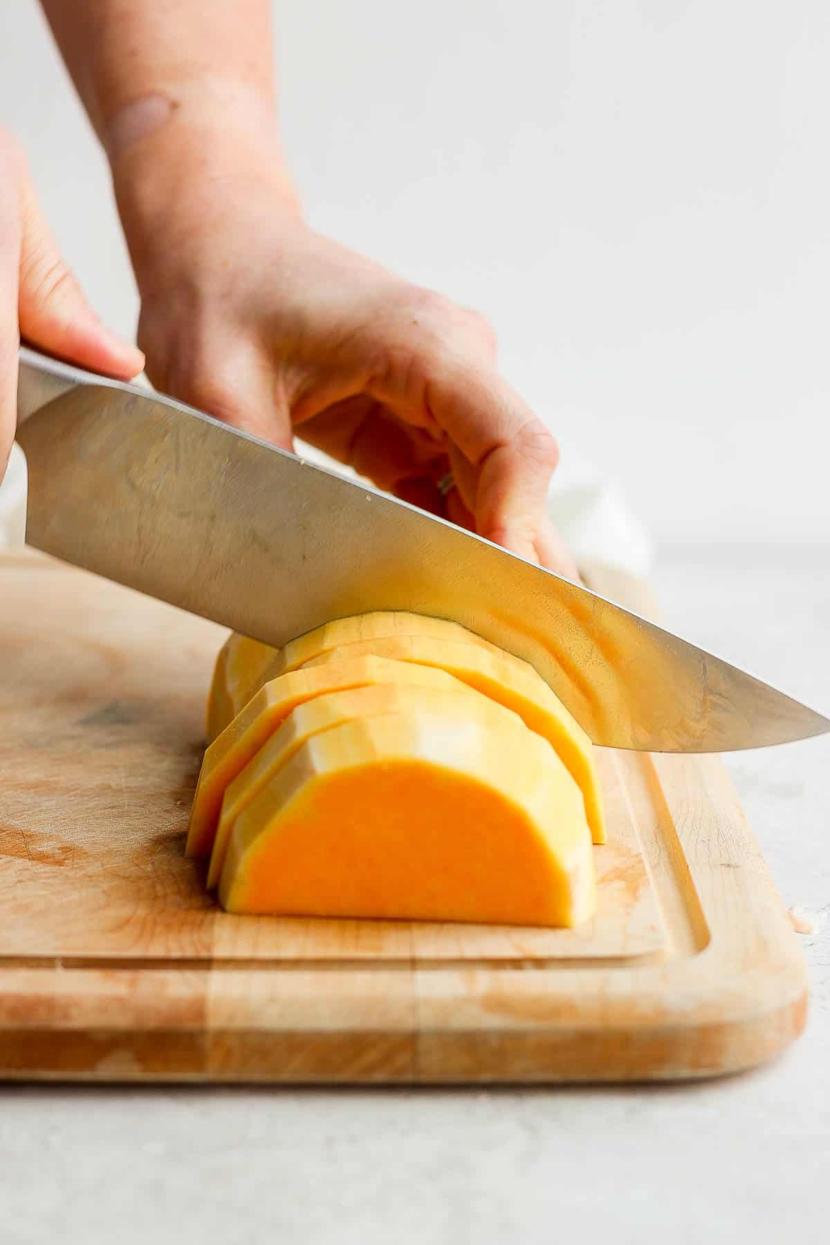 A section of butternut squash being cut into slices.