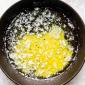 A small cast iron skillet with melted, smoked butter inside.