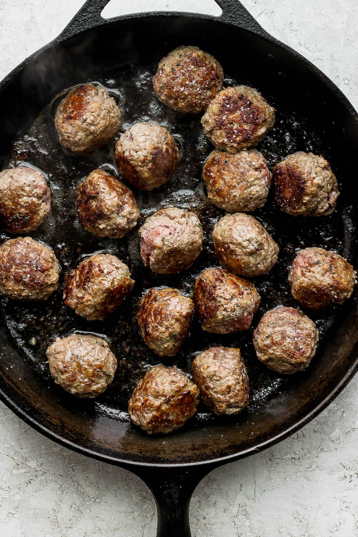 Seared meatballs in a cast iron skillet.