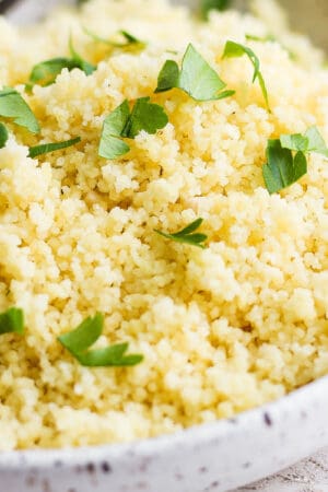 Side shot of a bowl of lemon couscous with fresh parsley on top.