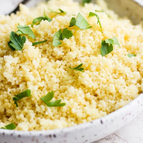 Side shot of a bowl of lemon couscous with fresh parsley on top.