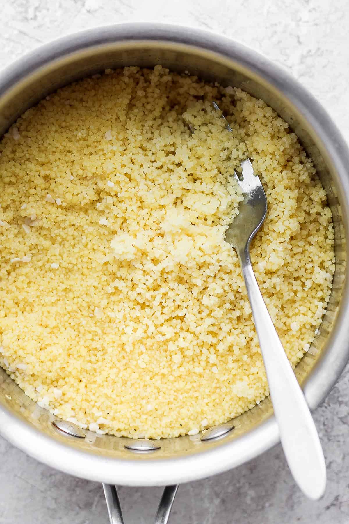 Steamed couscous being fluffed with a fork.